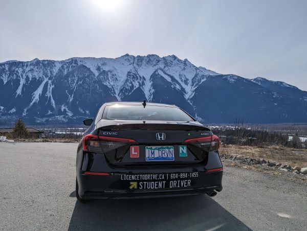 Student next to car with license